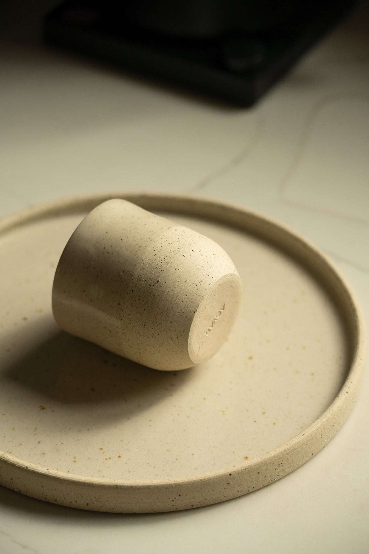 Small Coffee Cup in pale cream speckled stoneware, handmade with a rounded shape and unglazed base.