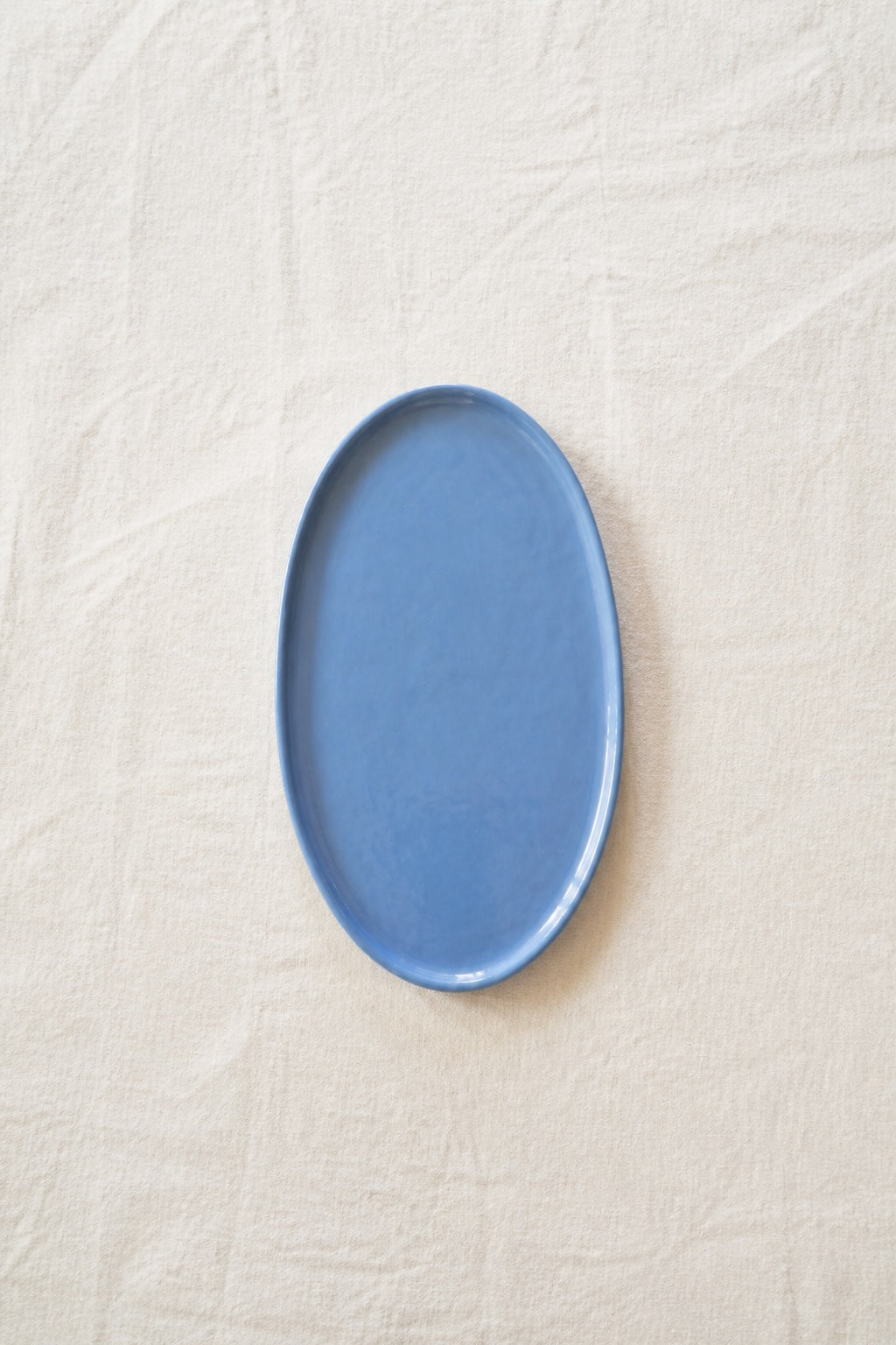 Porcelain Espresso Cup saucer in glossy blue glaze, with an elongated oval shape and gently raised rim.