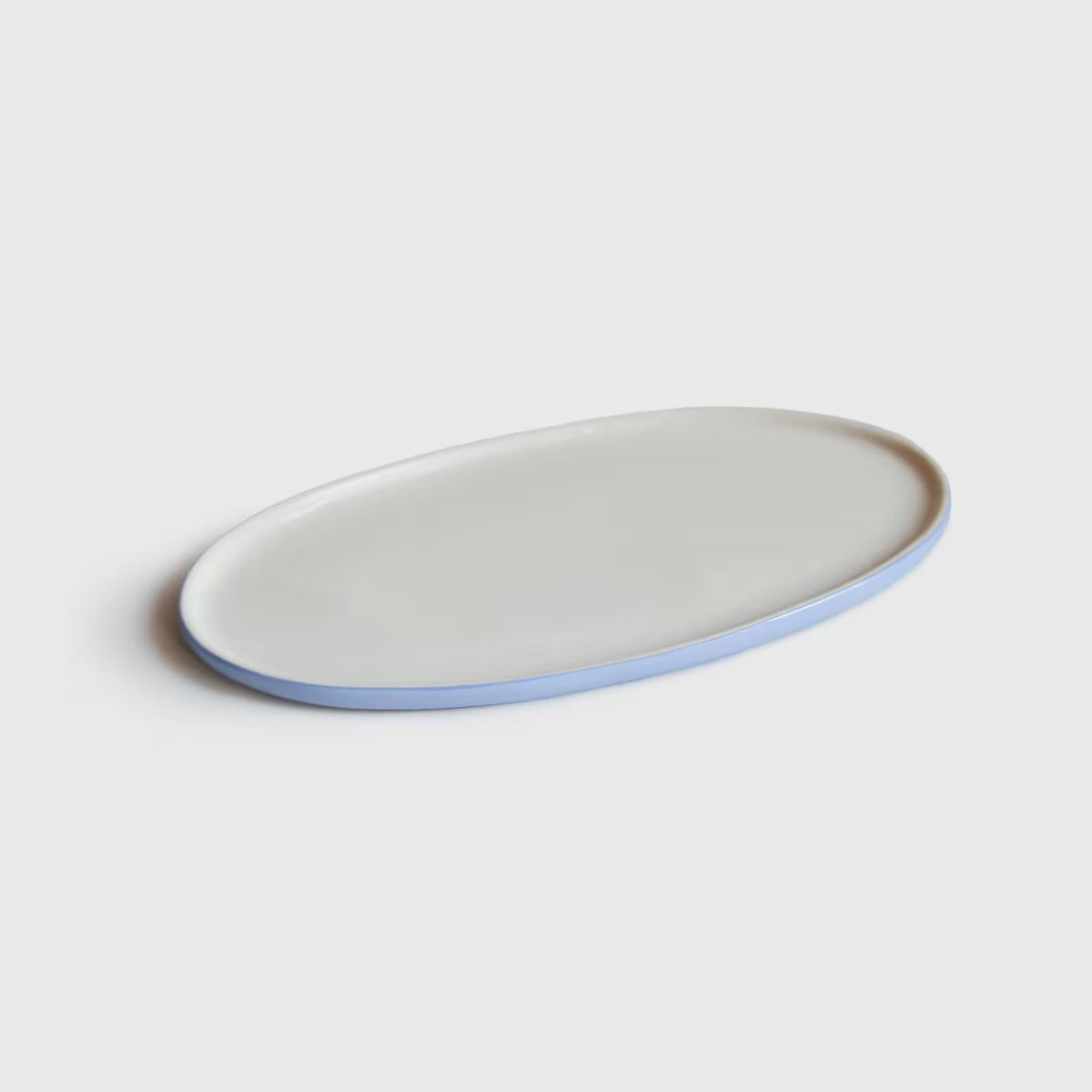 Porcelain Serving Platter with an oval shape, smooth white glazed center, and pale forget-me-not blue exposed rim.