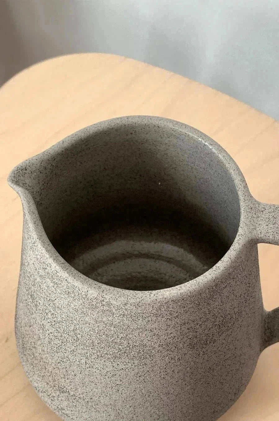 Handmade Stoneware Pitcher in speckled concrete-gray stoneware, with a matte textured finish, rounded body, spout and handle.