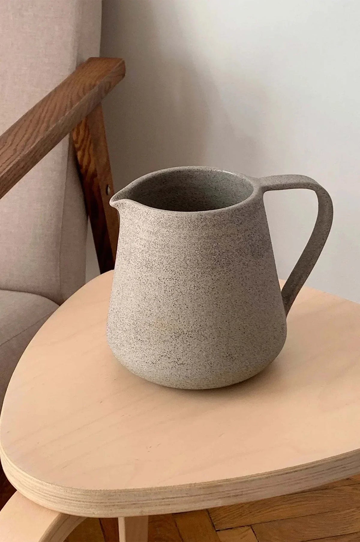 Handmade Stoneware Pitcher in speckled concrete-gray stoneware, with a matte finish, rounded body, spout and loop handle.