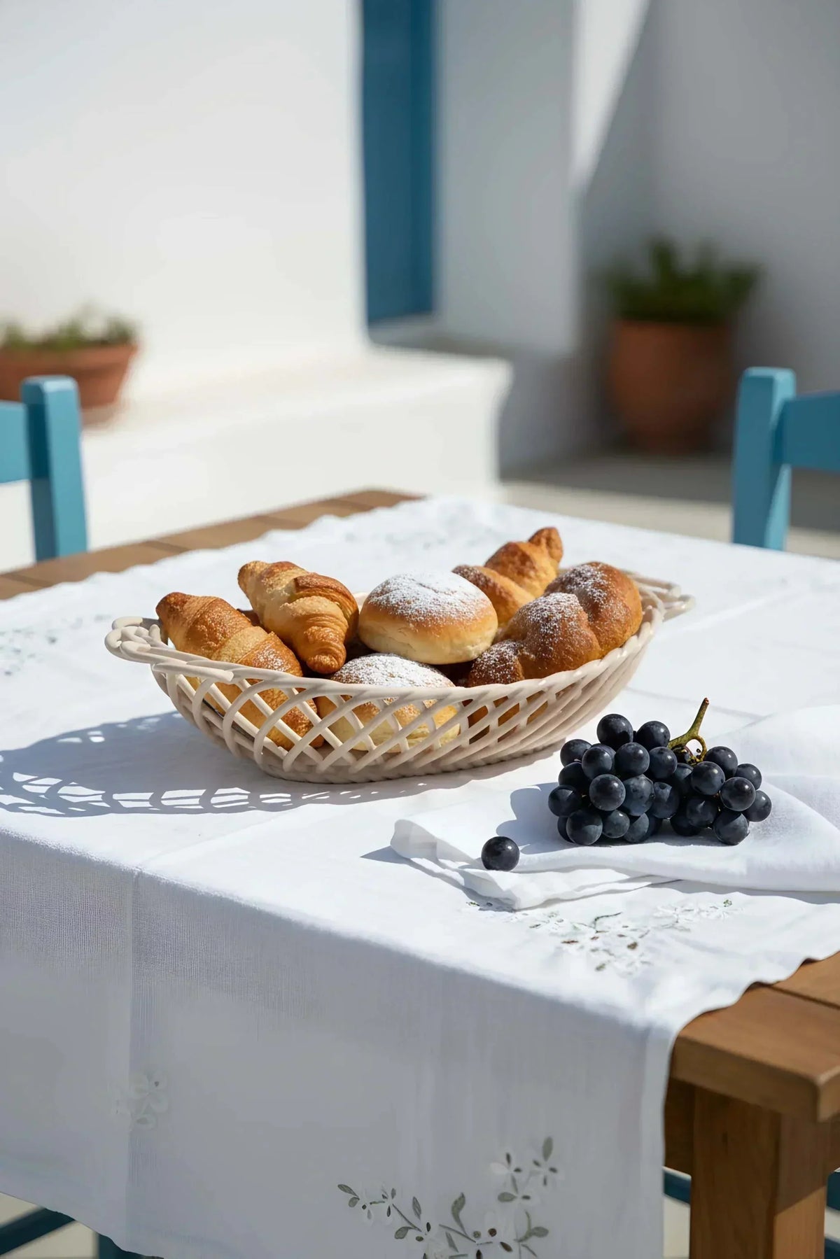 Ceramic Oval Basket in glossy ivory porcelain, with an open hand-woven lattice and oval shape holding pastries.