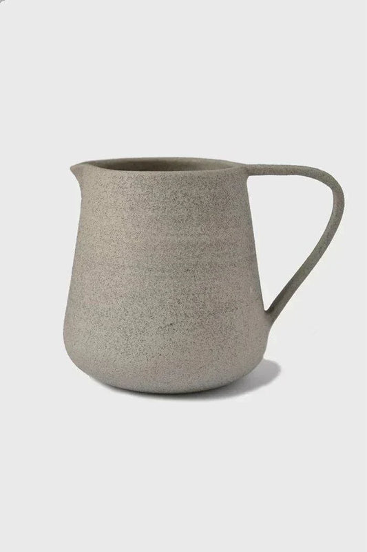 Handmade Stoneware Pitcher in speckled concrete-gray stoneware, with a matte textured finish, rounded body, and curved handle.
