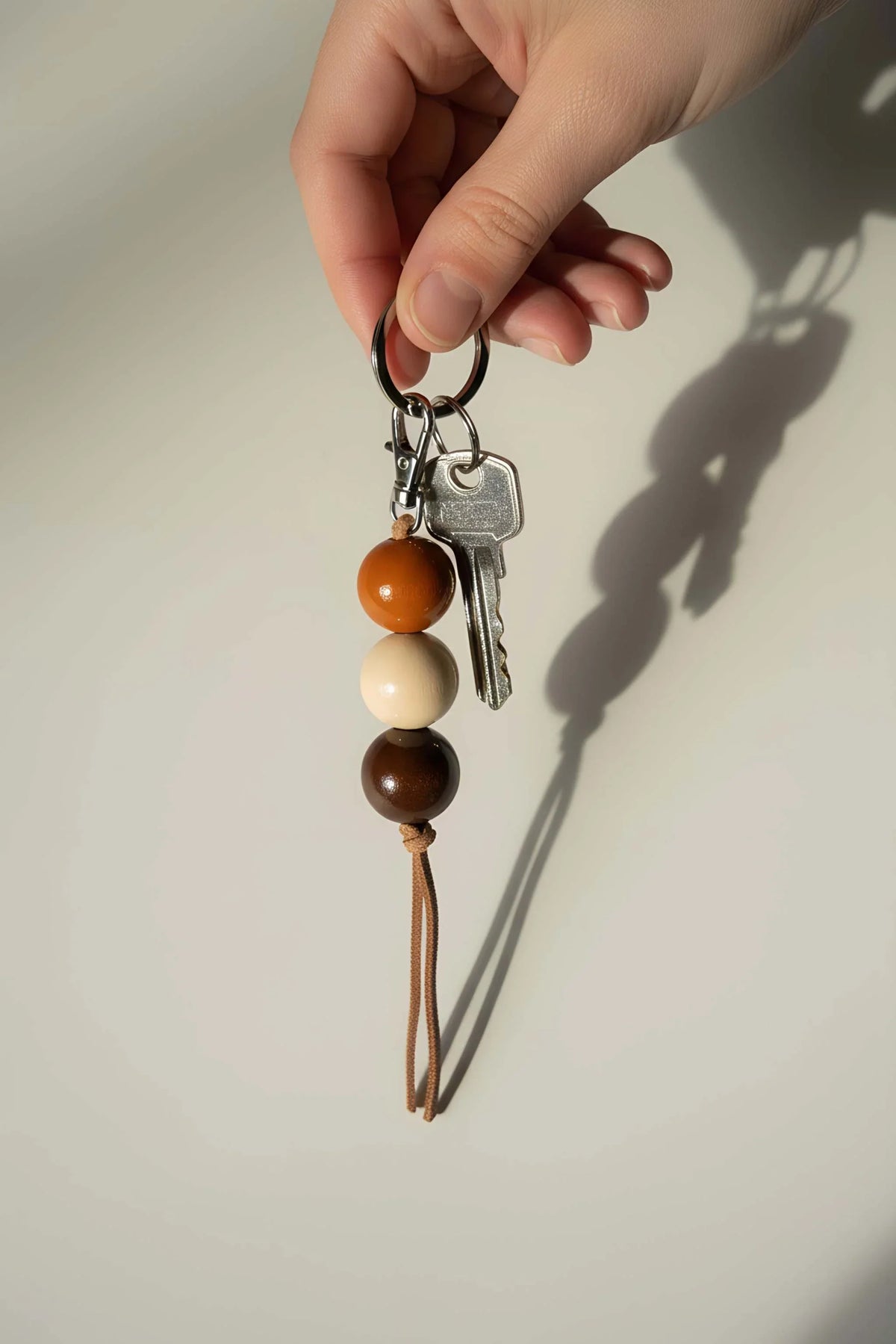 Ceramic Keychain with three smooth orange, cream, and dark brown beads, silver-tone keys, and a brown leather cord.