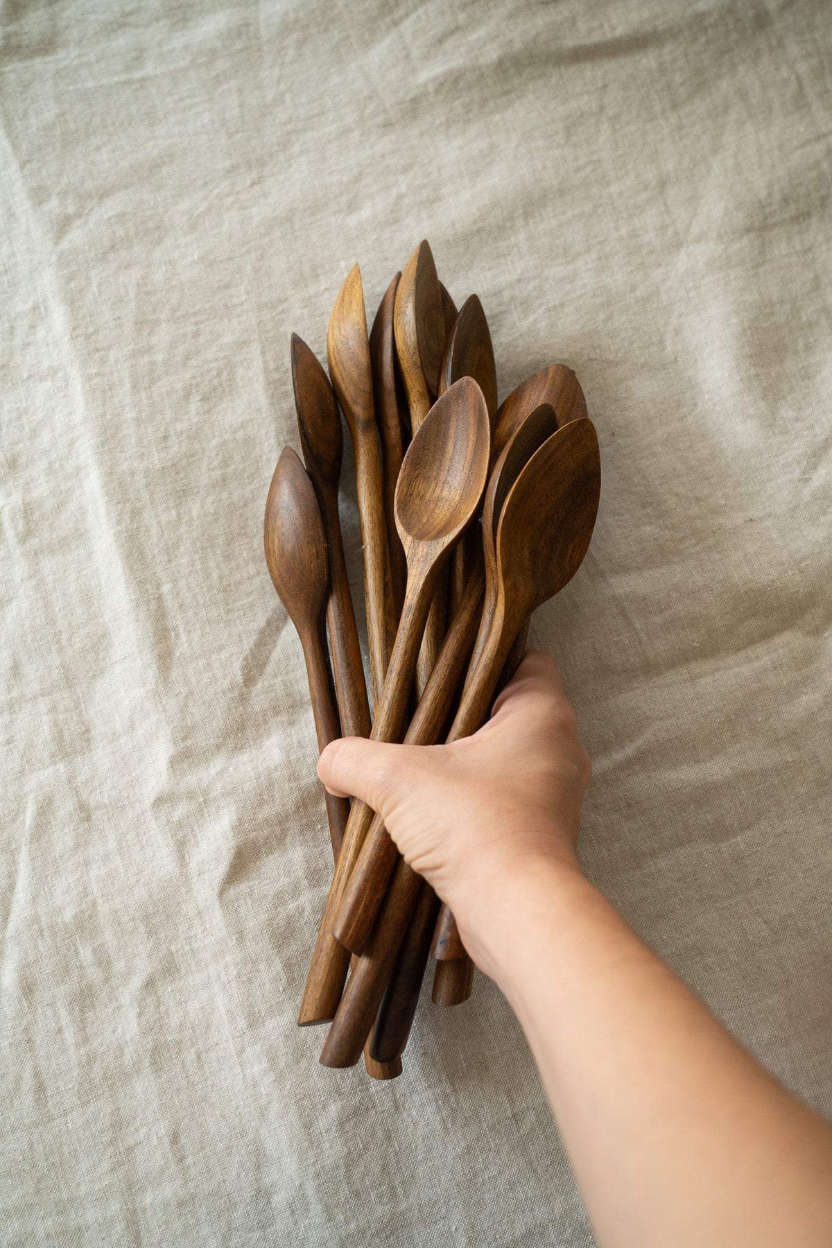 Soup Walnut Wood Spoon with a warm brown finish, natural grain, and a hand-carved shape; shown among wooden spoons.