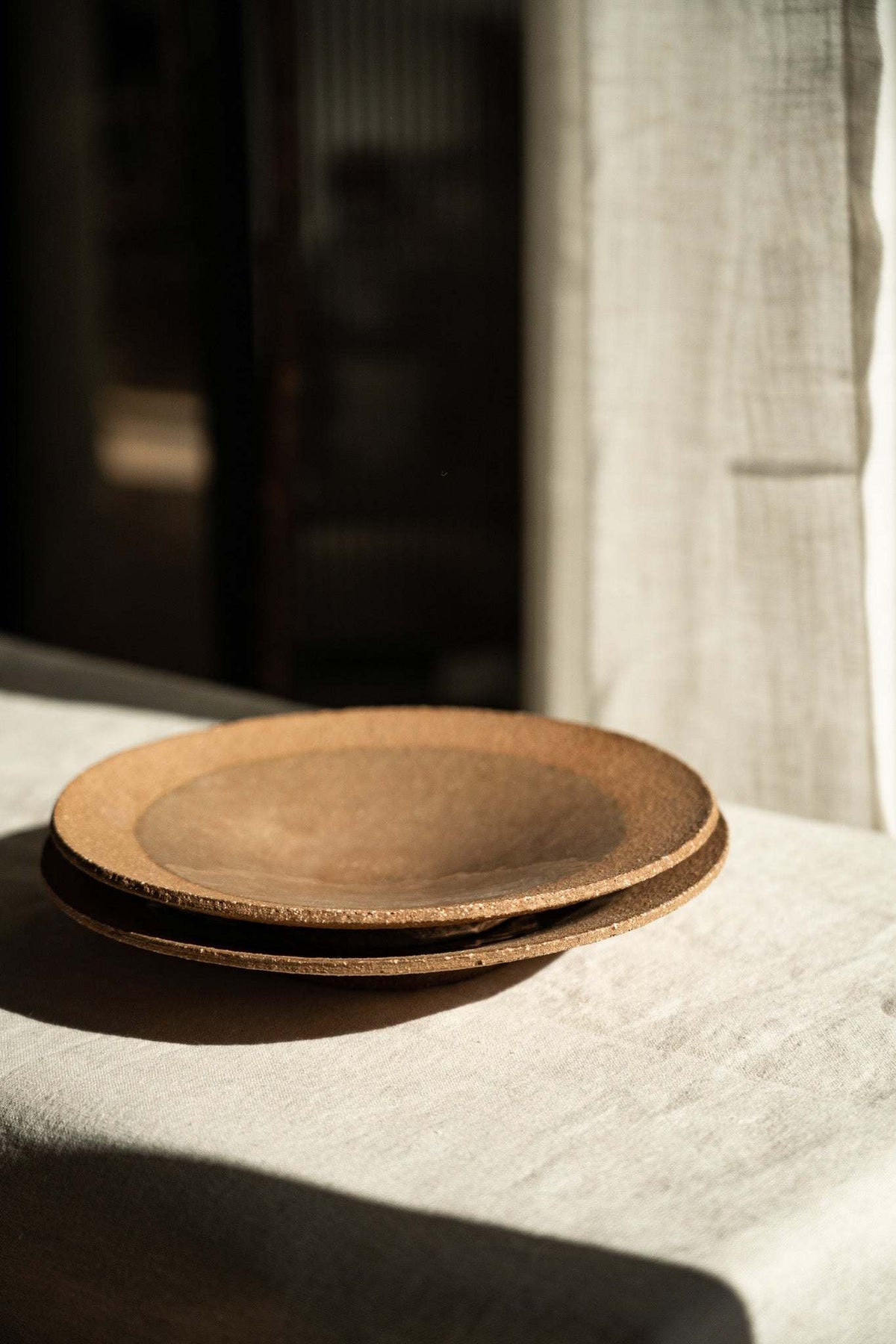 Handmade pinkish-red speckled stoneware pedestal plate with glossy center and unglazed rim
