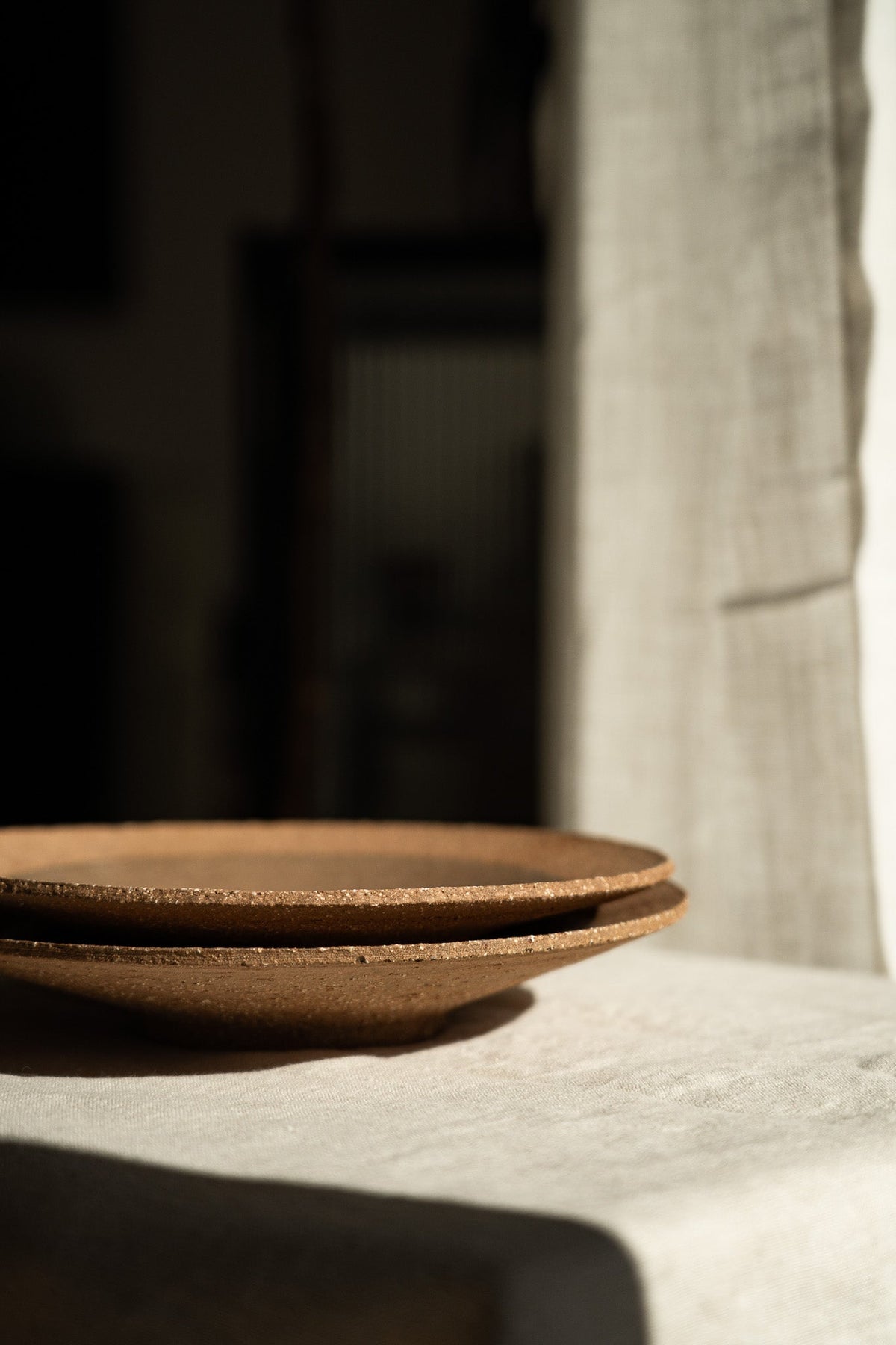 Handmade pinkish-red speckled stoneware pedestal plate with glossy center and unglazed rim