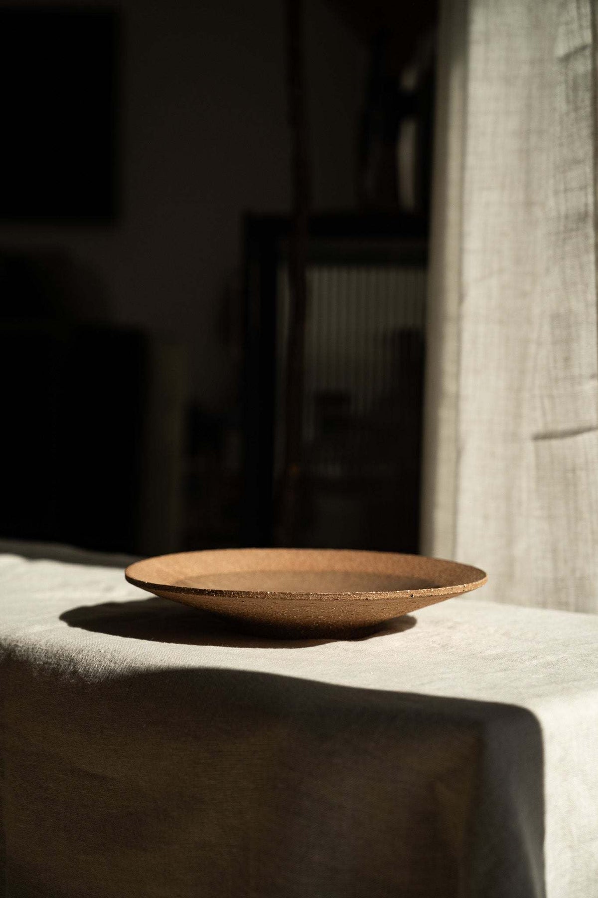 Handmade pinkish-red stoneware pedestal plate with natural speckles and glossy glazed center