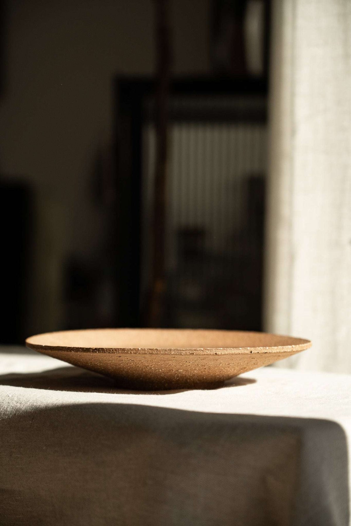 Handmade pinkish-red stoneware pedestal plate with speckles and glossy center glaze