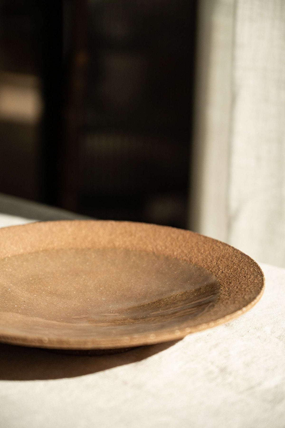 Handmade pinkish-red stoneware pedestal plate with speckles and glossy center