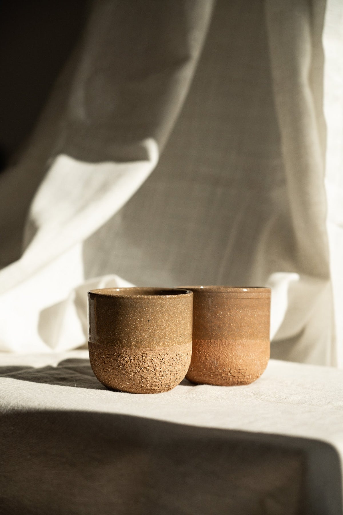Handmade Pottery Coffee Cup in earthy reddish-brown stoneware, with a subtly speckled textured lower half and smooth rim.