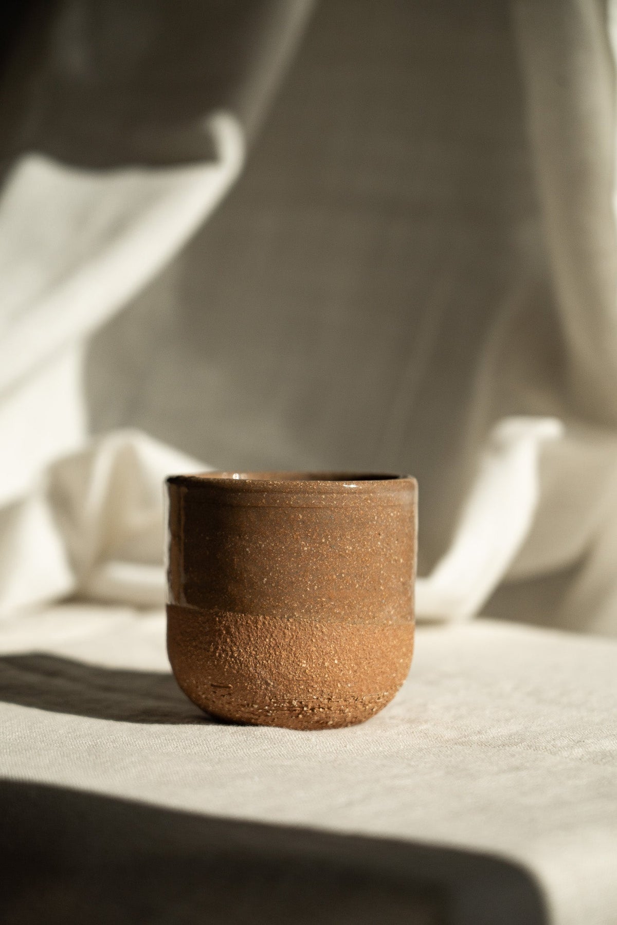 Handmade Pottery Coffee Cup in warm brown speckled stoneware with a glossy rim and rounded, handleless shape.