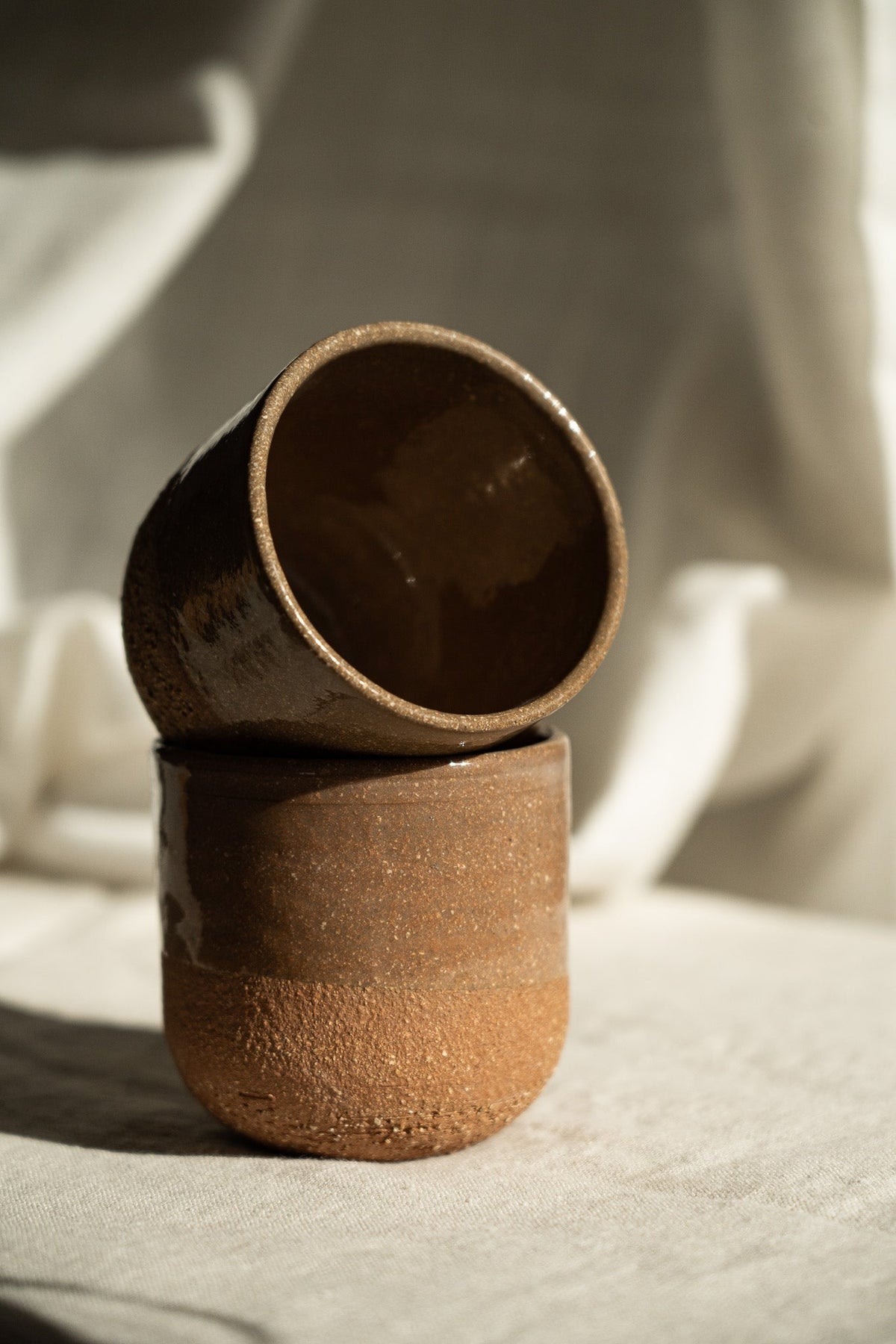 Handmade Pottery Coffee Cup in rustic reddish-brown stoneware, with glossy dark interiors and an unglazed textured finish.