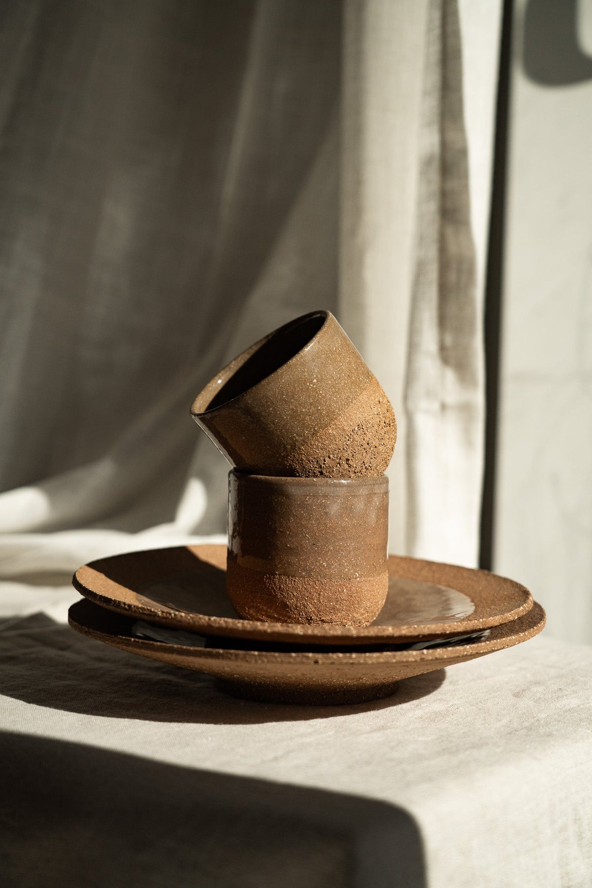 Handmade Pottery Coffee Cup in earthy reddish-brown stoneware with a rough speckled finish and matching saucer.