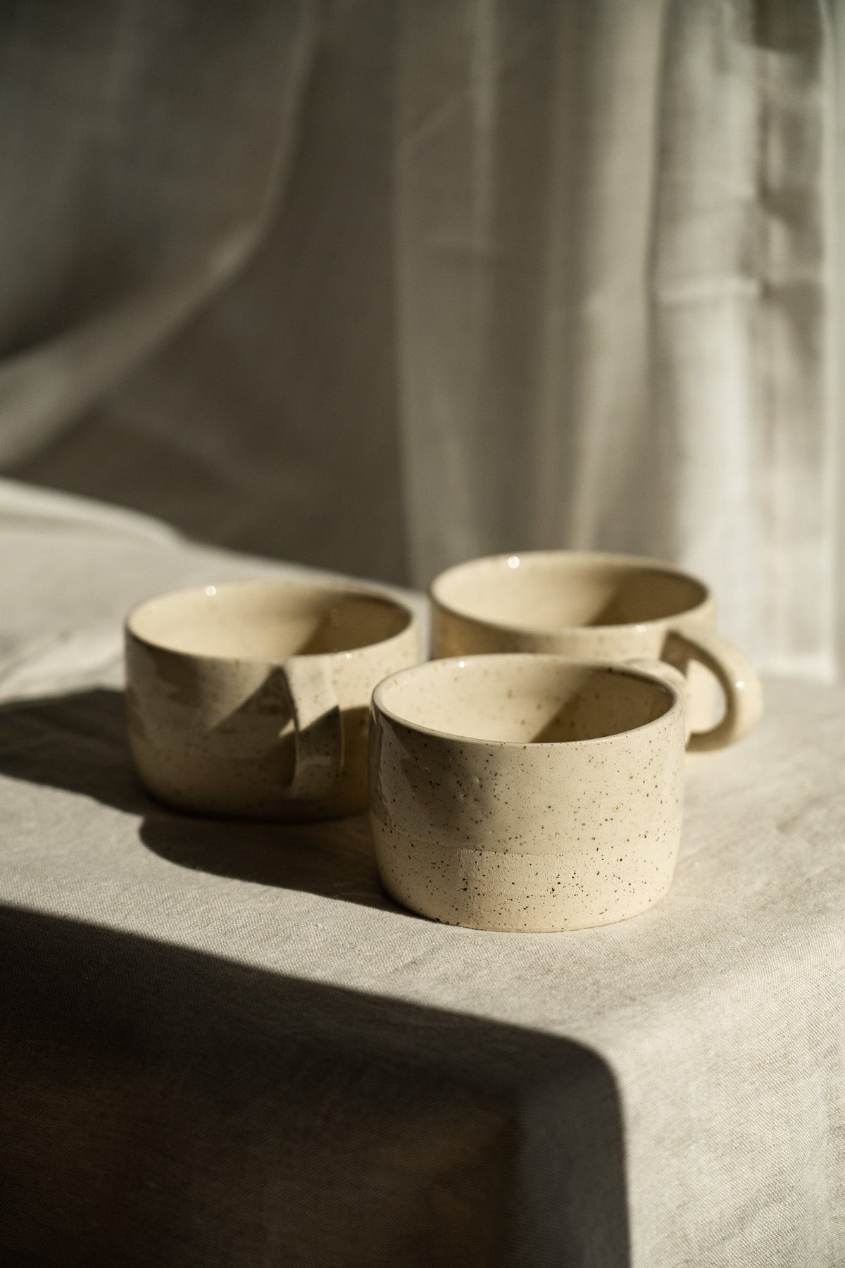 Handmade Stoneware Mug in warm ivory sand stoneware with fine dark speckles, rounded shape, and a small loop handle.