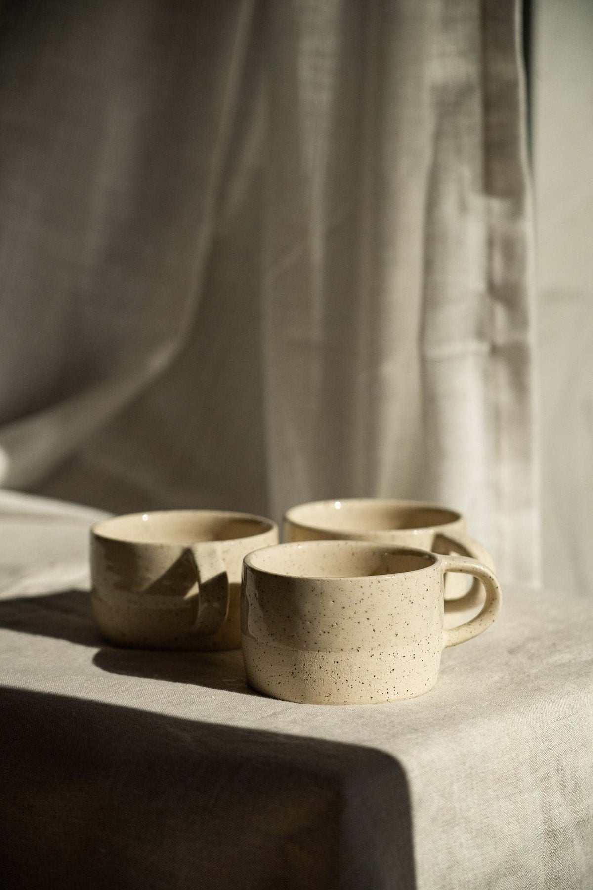 Handmade Stoneware Mug in warm ivory sand stoneware, with fine dark speckles, rounded shape and loop handle.