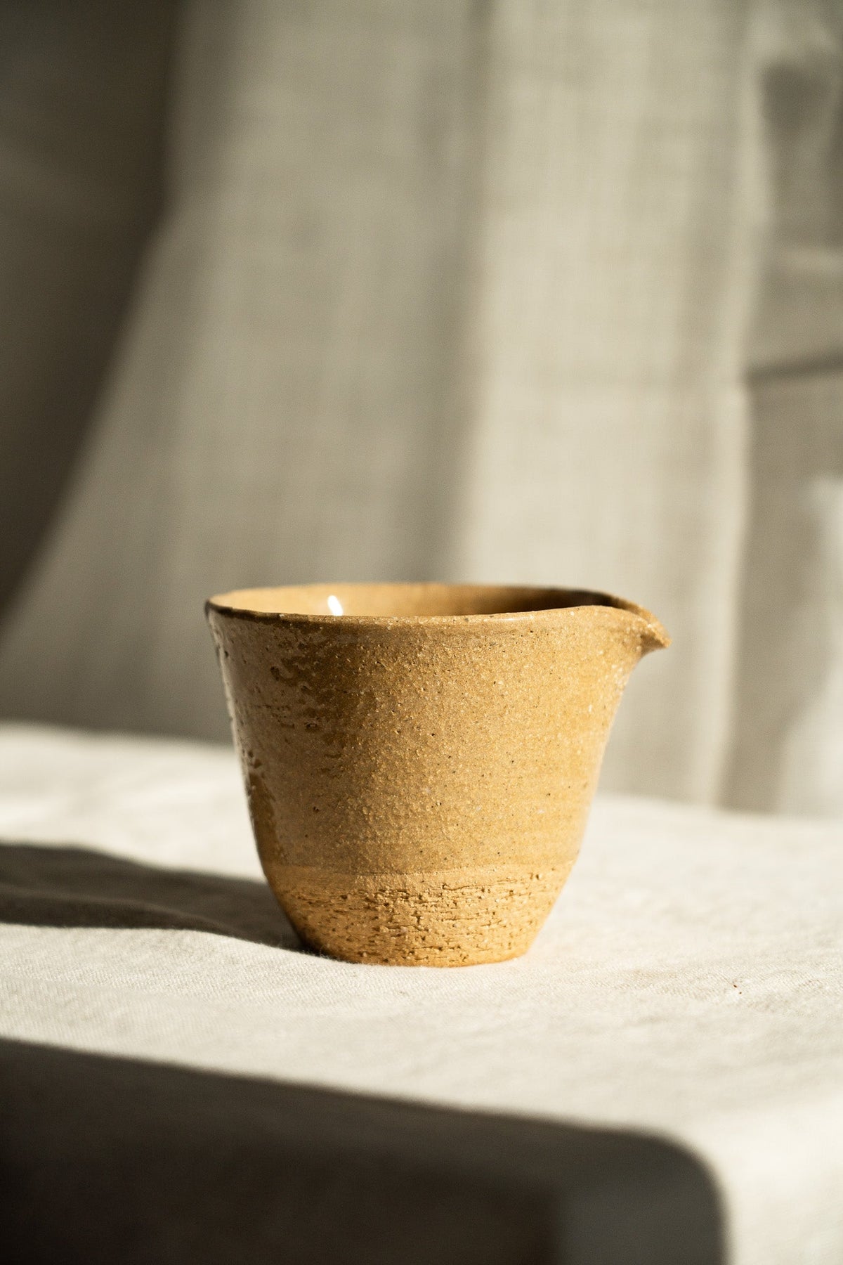 Handmade Stoneware Fair Teacup in golden yellow with a speckled, textured glaze and a small pouring spout.