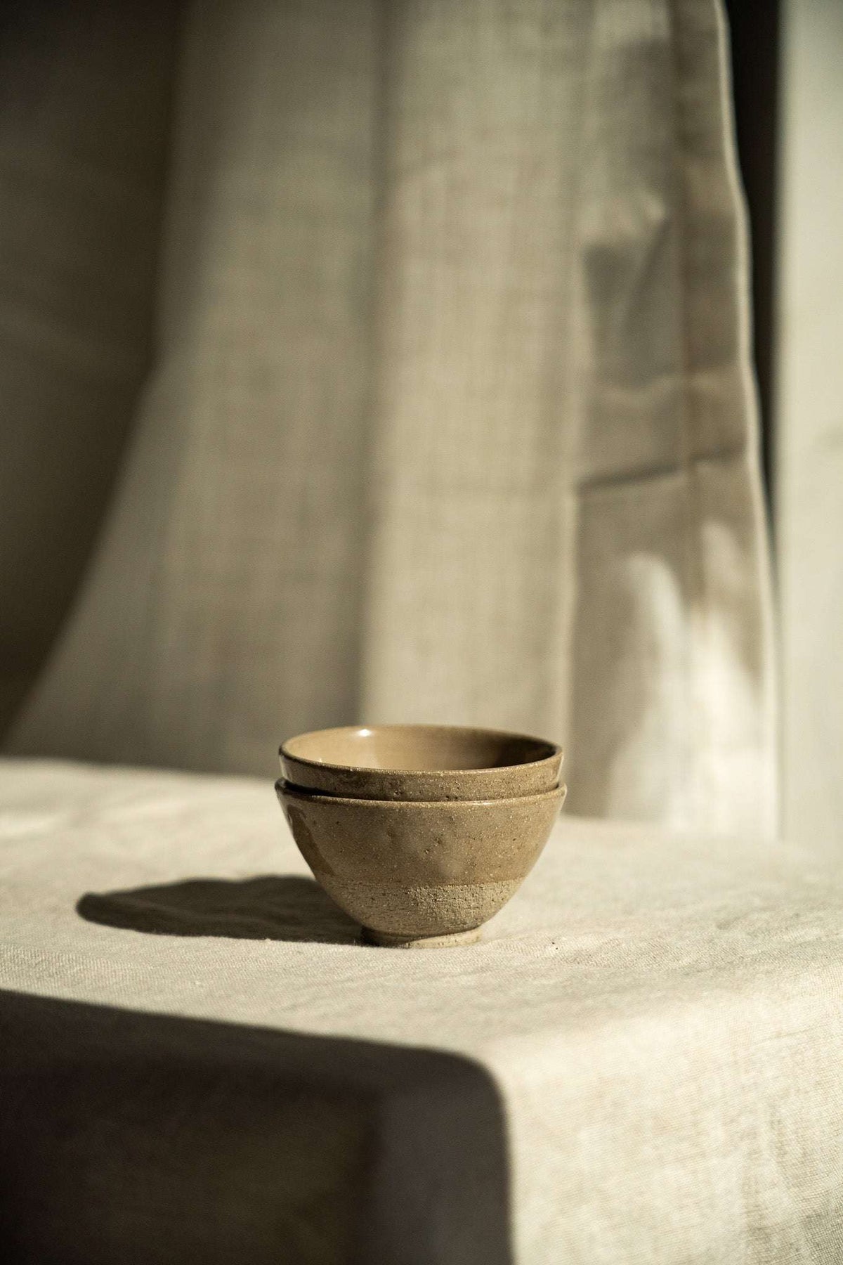 Handmade Stoneware Small Tea Cup in warm gray-brown, with a speckled matte exterior and dark glazed rim and interior.