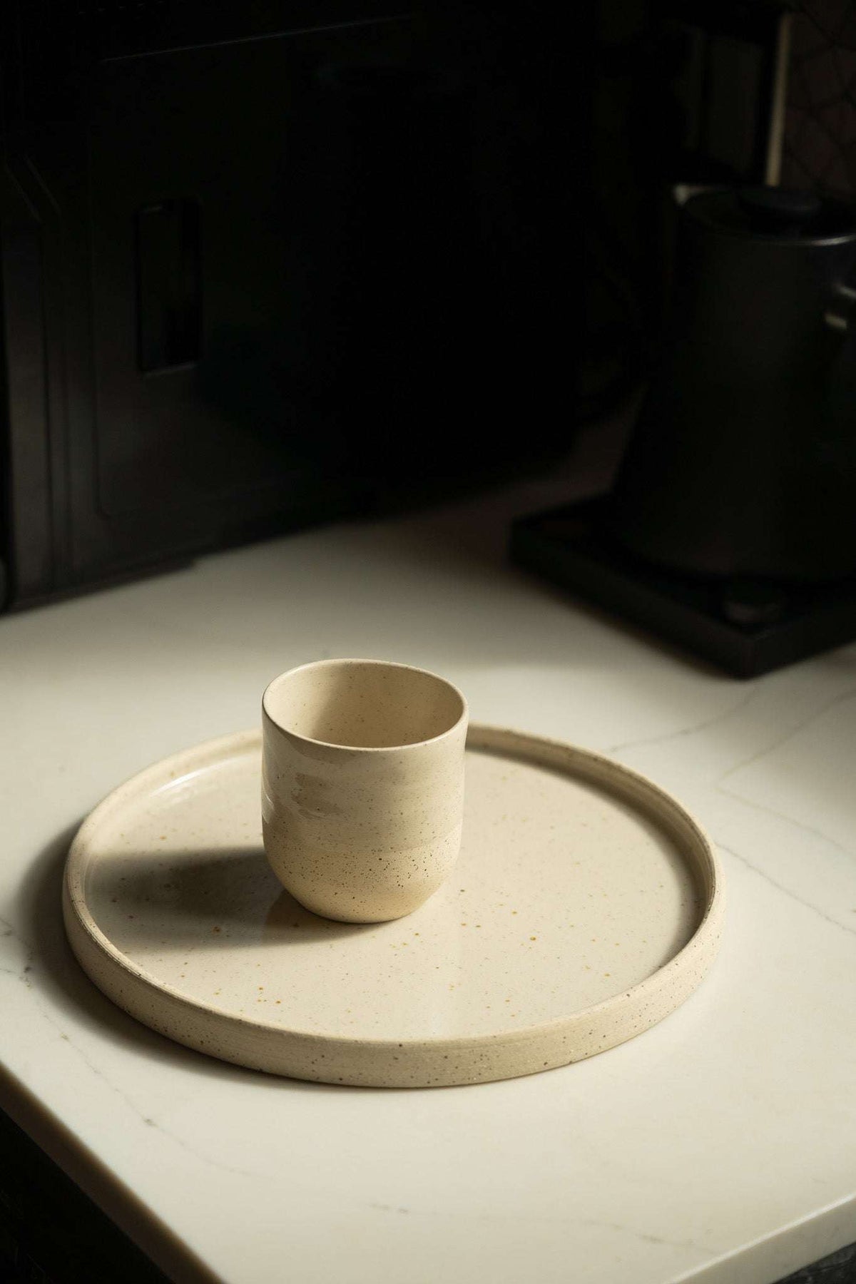 Stoneware Pottery Plate in speckled cream stoneware, with a raised rim and a small matching cup centered on top.