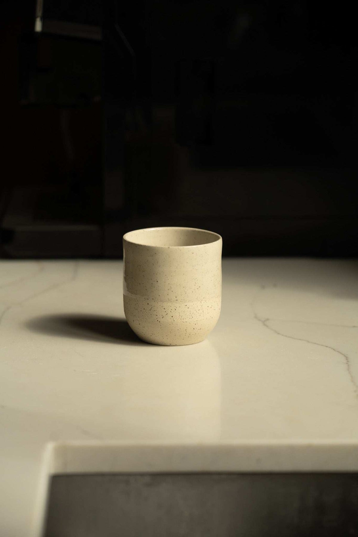 Small Coffee Cup in cream speckled stoneware, with a glossy glazed finish and simple rounded shape.