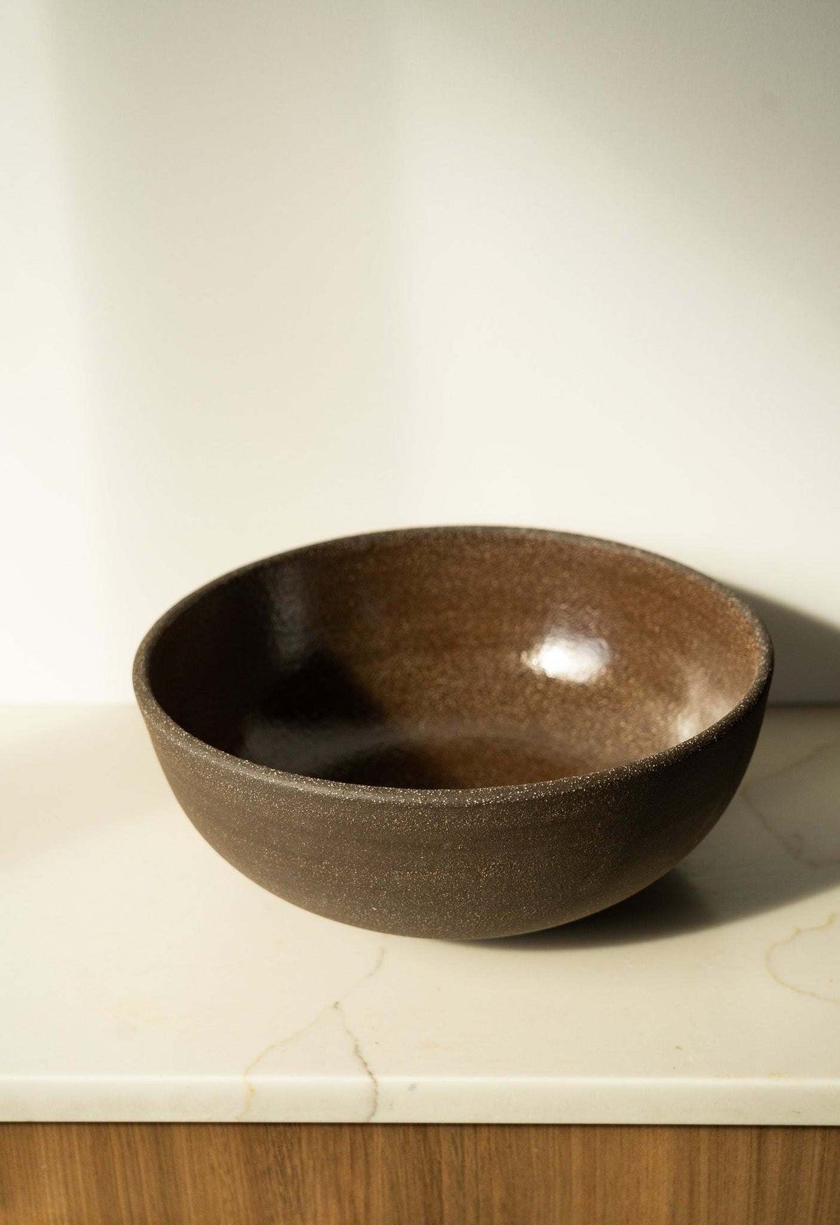Stoneware Large Fruit Bowl in dark brown with a smooth glossy interior and subtly speckled, textured exterior.
