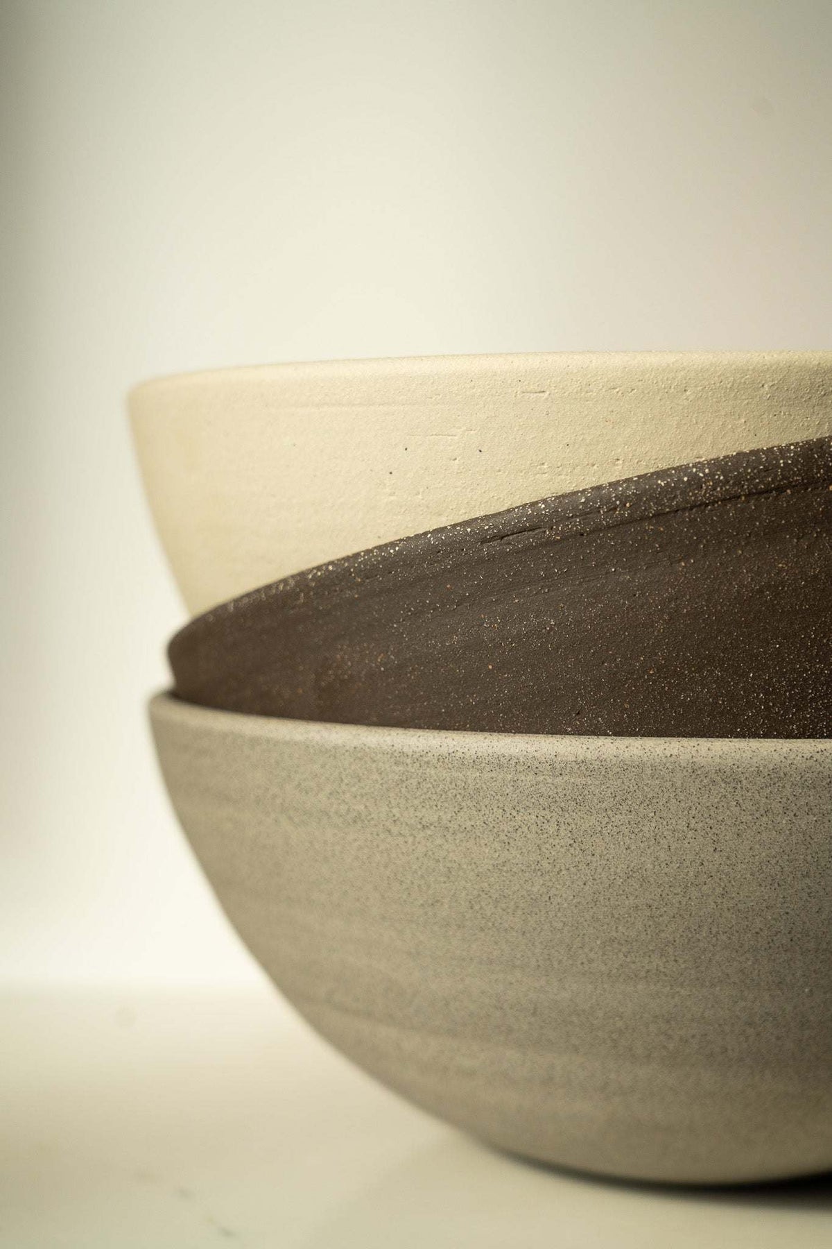 Stoneware Large Fruit Bowl in muted taupe with a rough, speckled exterior and a smooth rounded shape.
