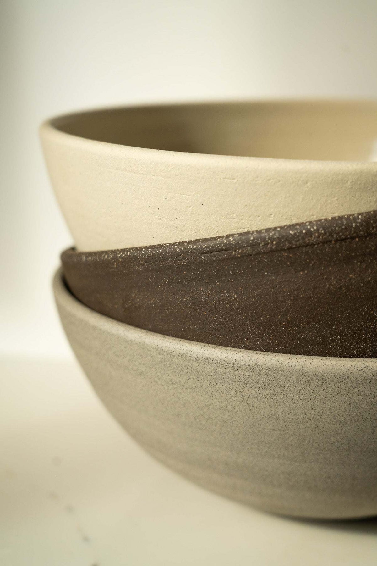 Stoneware Large Fruit Bowl set in cream, dark brown, and gray, with matte glaze and gently rounded forms.