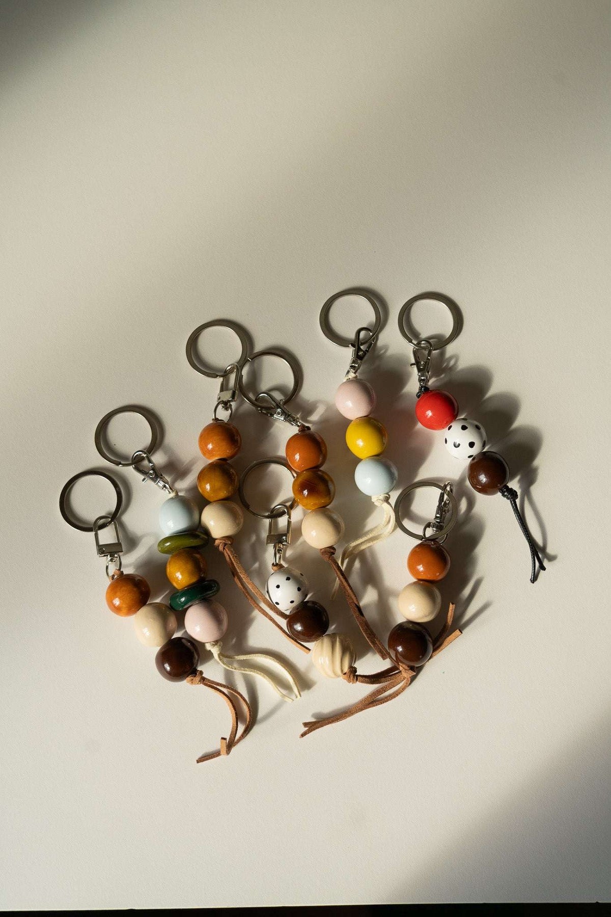 Ceramic Beaded Keychain with glossy brown, orange, cream and pastel beads, leather cord tassels, and silver-tone rings.