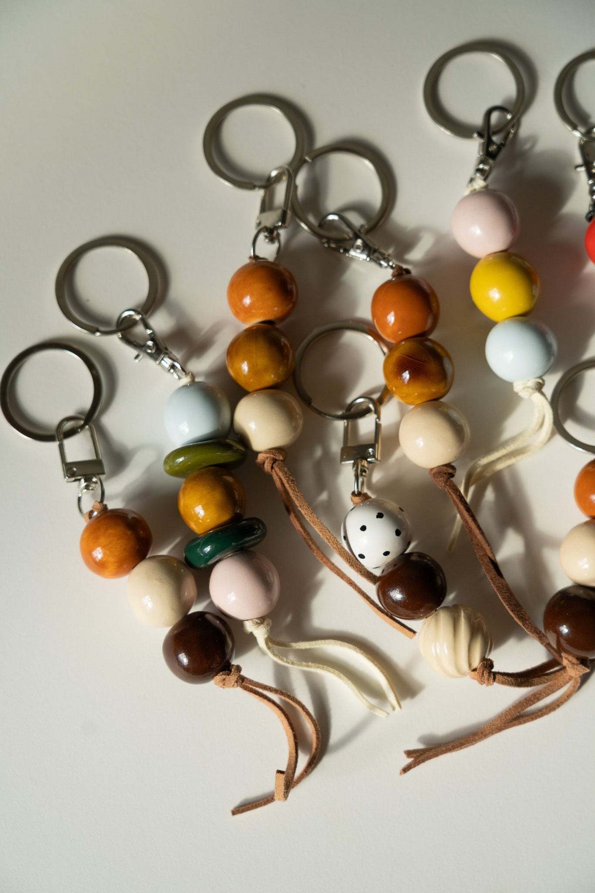 Ceramic Beaded Keychain with glossy orange, brown, cream and pastel beads, leather cord and silver-tone ring fittings.