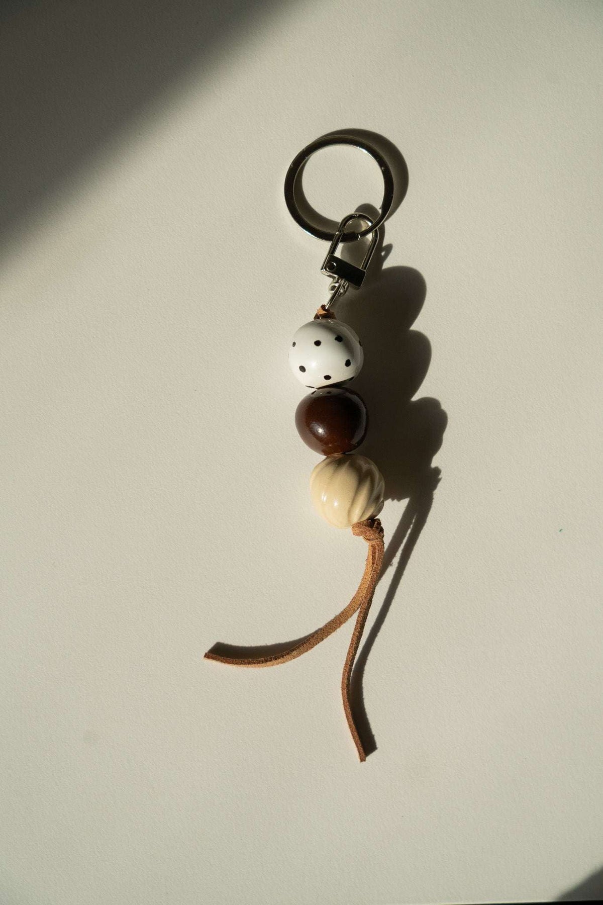 Ceramic Beaded Keychain with white, dark brown, and cream ceramic beads, black speckles, and a leather cord.