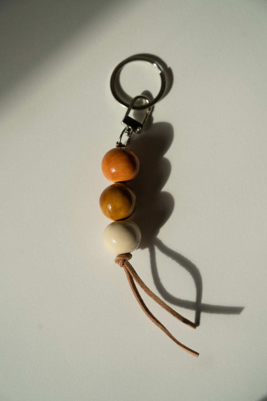 Handmade Ceramic Beaded Keychain with three glossy orange, amber, and cream beads, brown leather cords, and silver-tone hardware.
