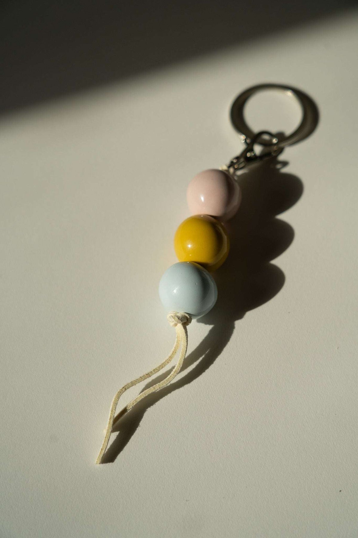 Ceramic Beaded Keychain with glossy pink, yellow, and pale blue round beads, cream cord, and silver-tone ring and chain.