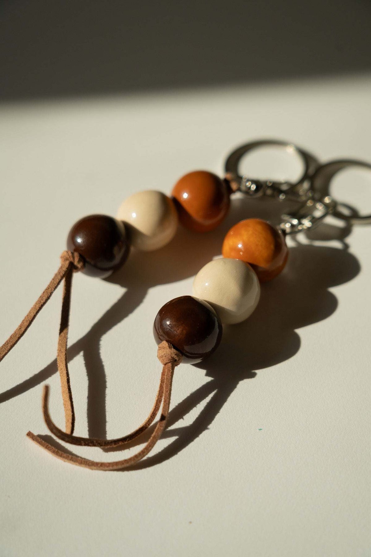 Ceramic Keychain with glossy dark brown, cream, and amber beads on a tan leather cord and silver-tone ring chain.