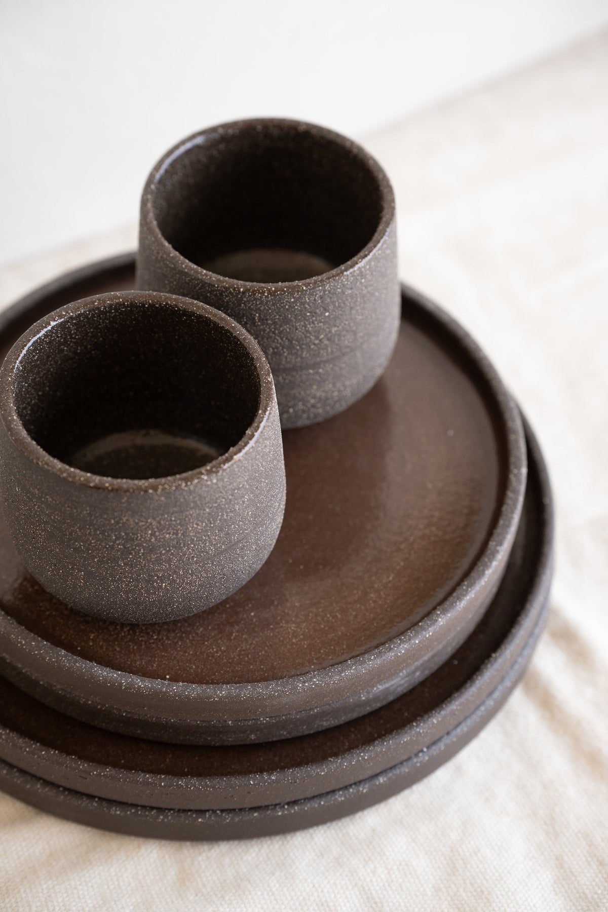 Handmade stoneware dinner plates in pumpernickel color with natural rough exterior and smooth glazed interior