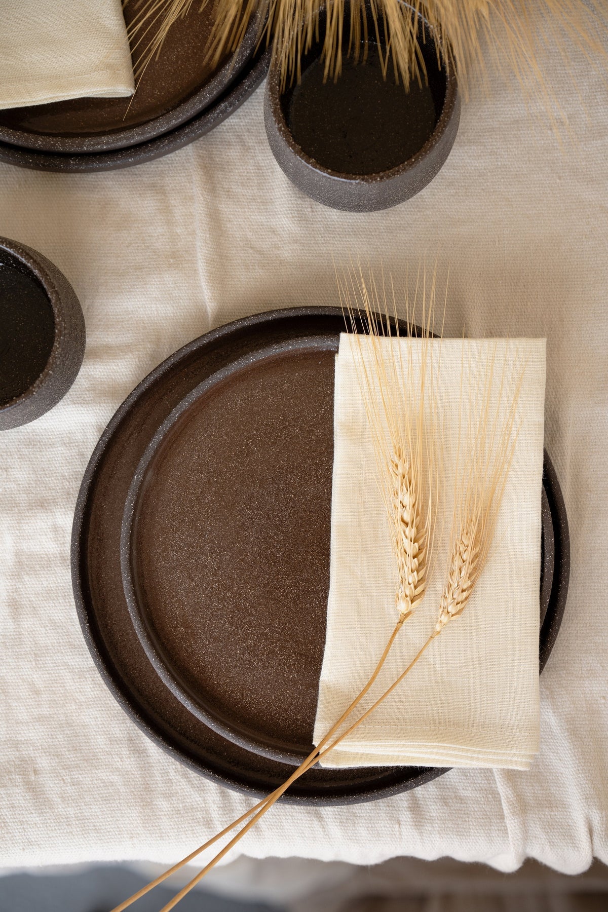 Handmade stoneware dinner plates in dark pumpernickel color with smooth glazed interior and rough exterior