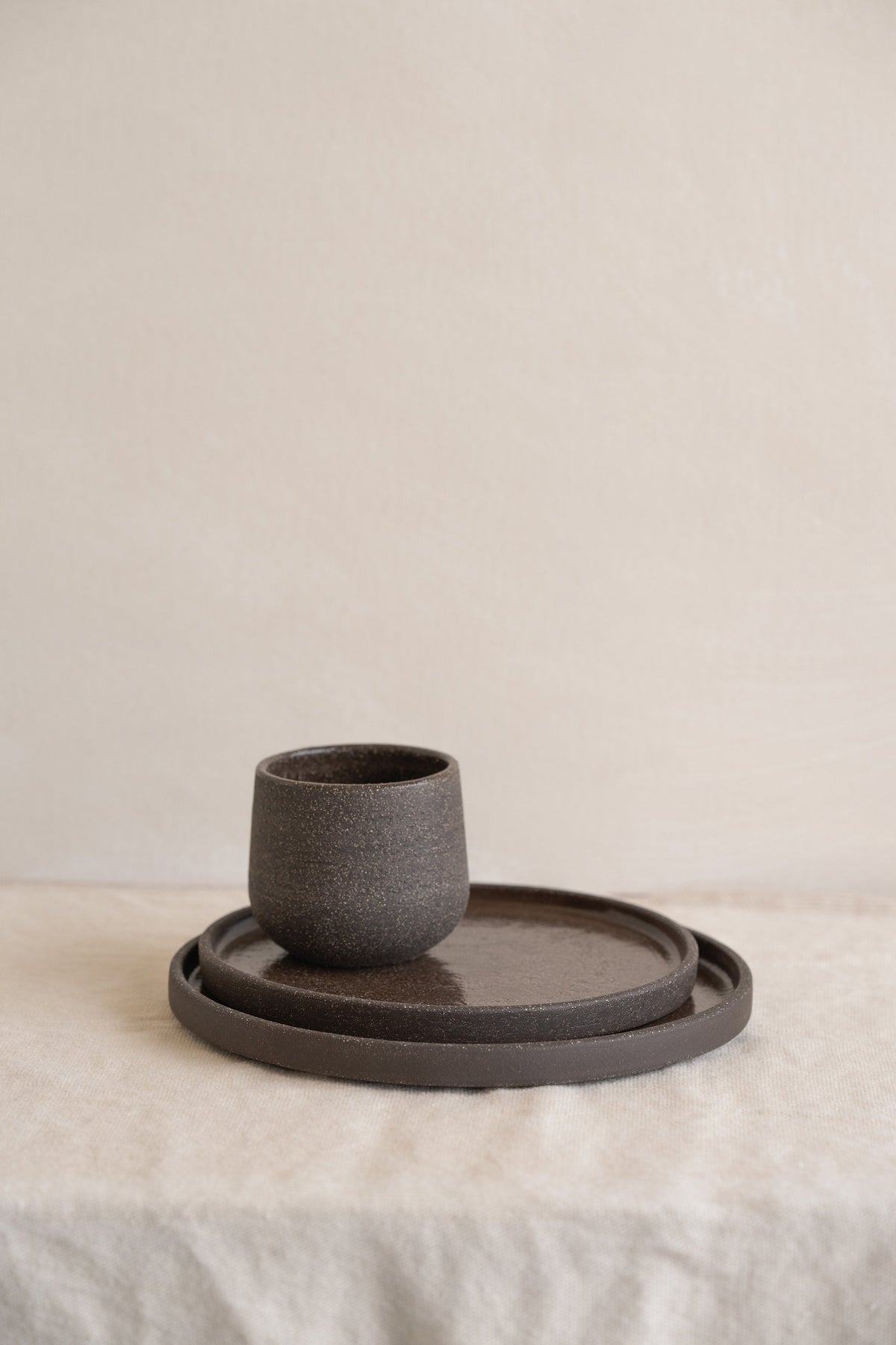 Handmade stoneware dinner plates in pumpernickel color with rough exterior and smooth glazed interior