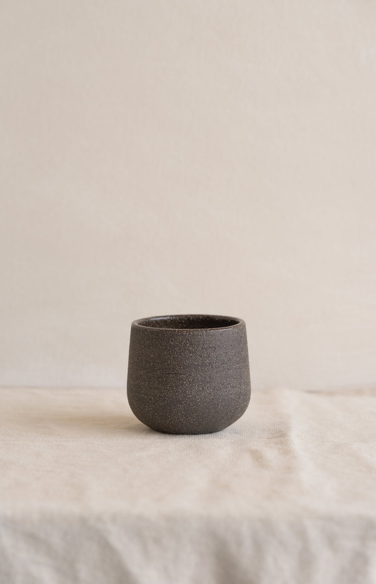 Handmade stoneware coffee cup in pumpernickel color with glazed interior, durable and food-safe
