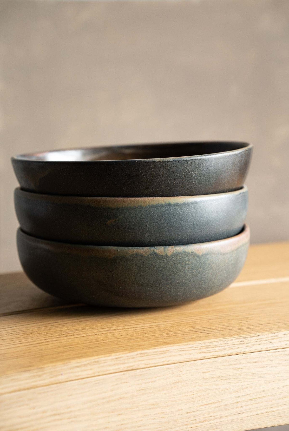 Stoneware pasta bowl stack in dark charcoal and grey stoneware with smooth, softly varied reactive glaze and rounded rims.