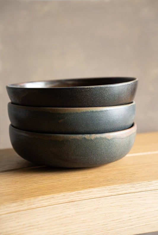 Stoneware pasta bowl stack in dark charcoal and grey stoneware with smooth, softly varied reactive glaze and rounded rims.