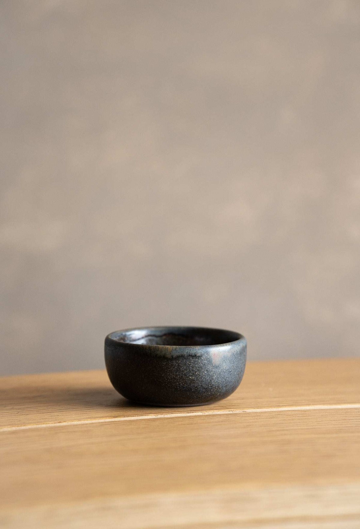 Rust Stoneware Pinch Bowl, small dark charcoal stoneware with a glossy speckled glaze and rounded shape.