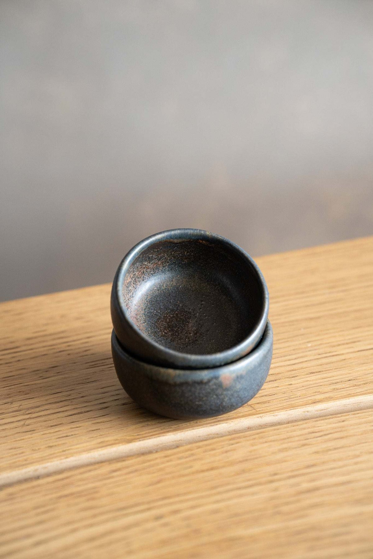 Rust Stoneware Pinch Bowl in dark charcoal with mottled rust-brown glaze, rounded shape and gently flared rim.
