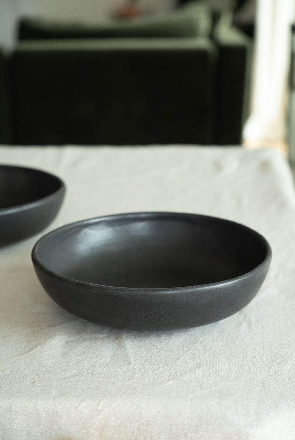 Black matte stoneware pasta bowl with a smooth finish, shallow wide shape, and gently curved sides.