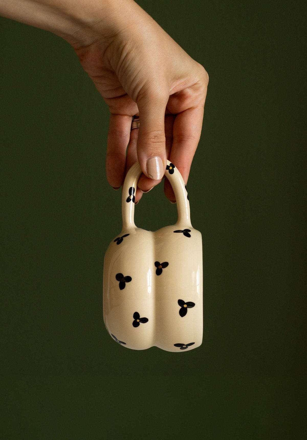 Bubble Mug in cream glazed ceramic with black three-petal flowers and a sculptural double-bulge shape with loop handle