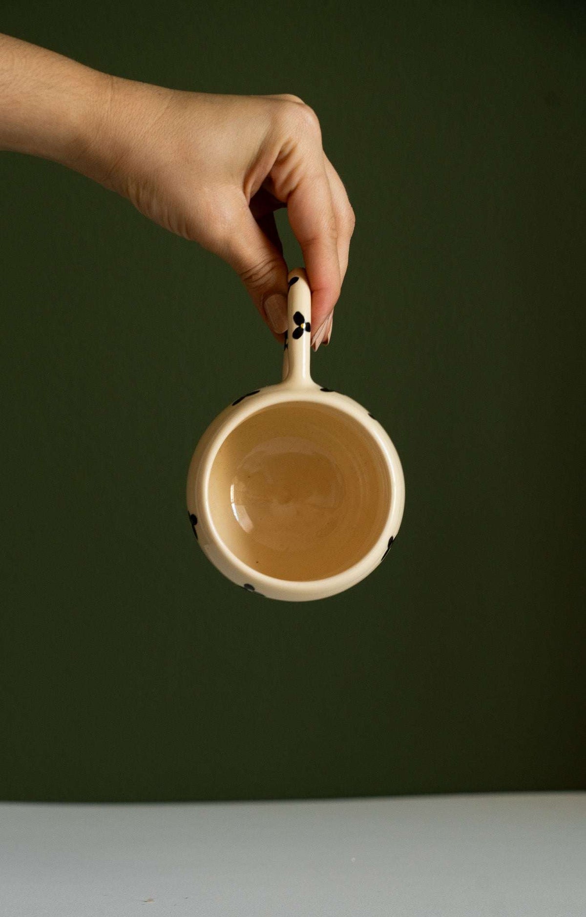 Bubble Mug in cream ceramic with a rounded double-ring shape and black floral accents on its handle and rim.