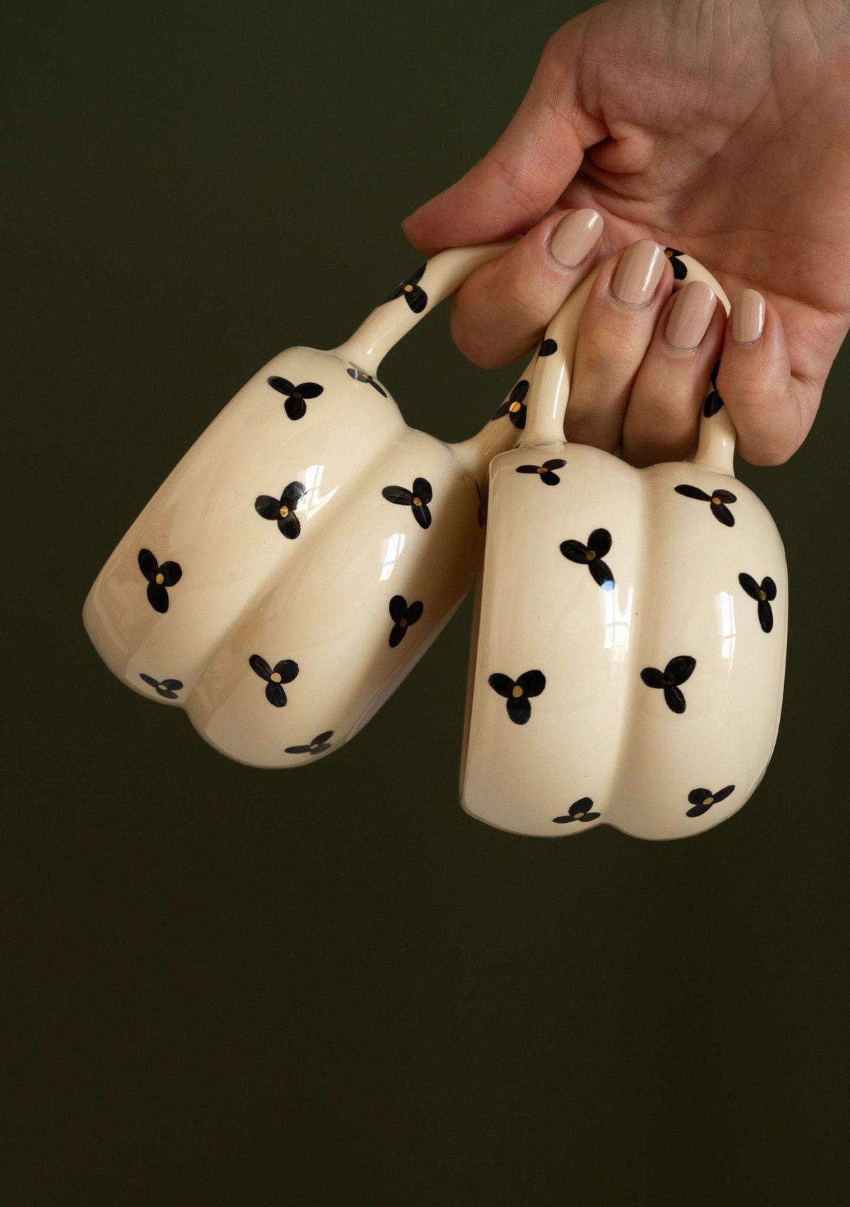 Bubble Mug with cream glazed ceramic, black three-petal flower pattern, and sculptural double-ring body with long handles.
