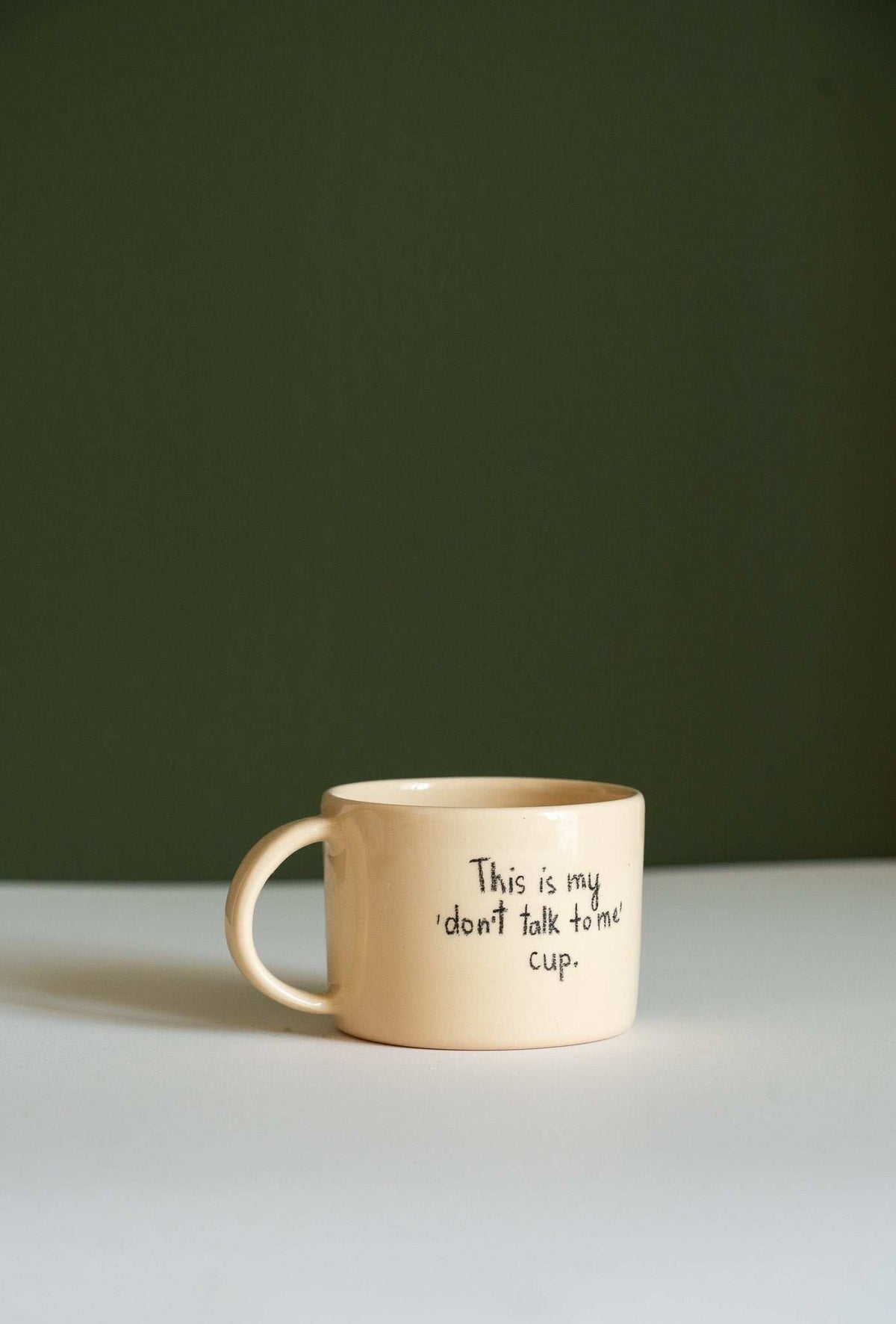 Personalized Stoneware Mug in cream ceramic with a rounded handle and handwritten black “This is my don’t talk to me cup” text.