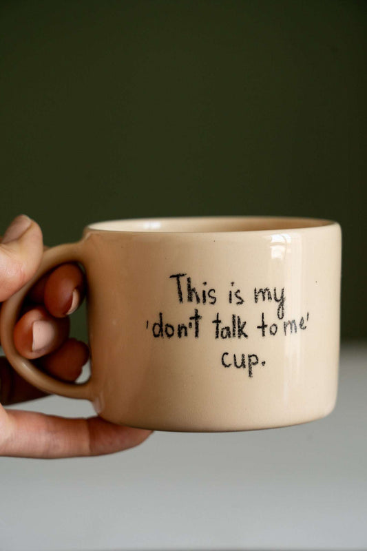 Personalized Stoneware Mug in pale beige glazed ceramic, with a rounded handle and handwritten black “don't talk to me” message.
