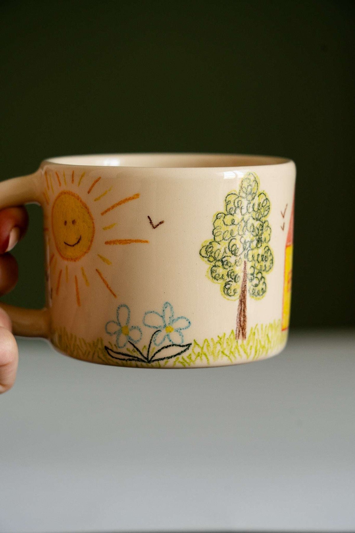 Kids Artwork Stoneware Mug in cream beige ceramic, decorated with childlike crayon-style sun, tree, flowers and birds.