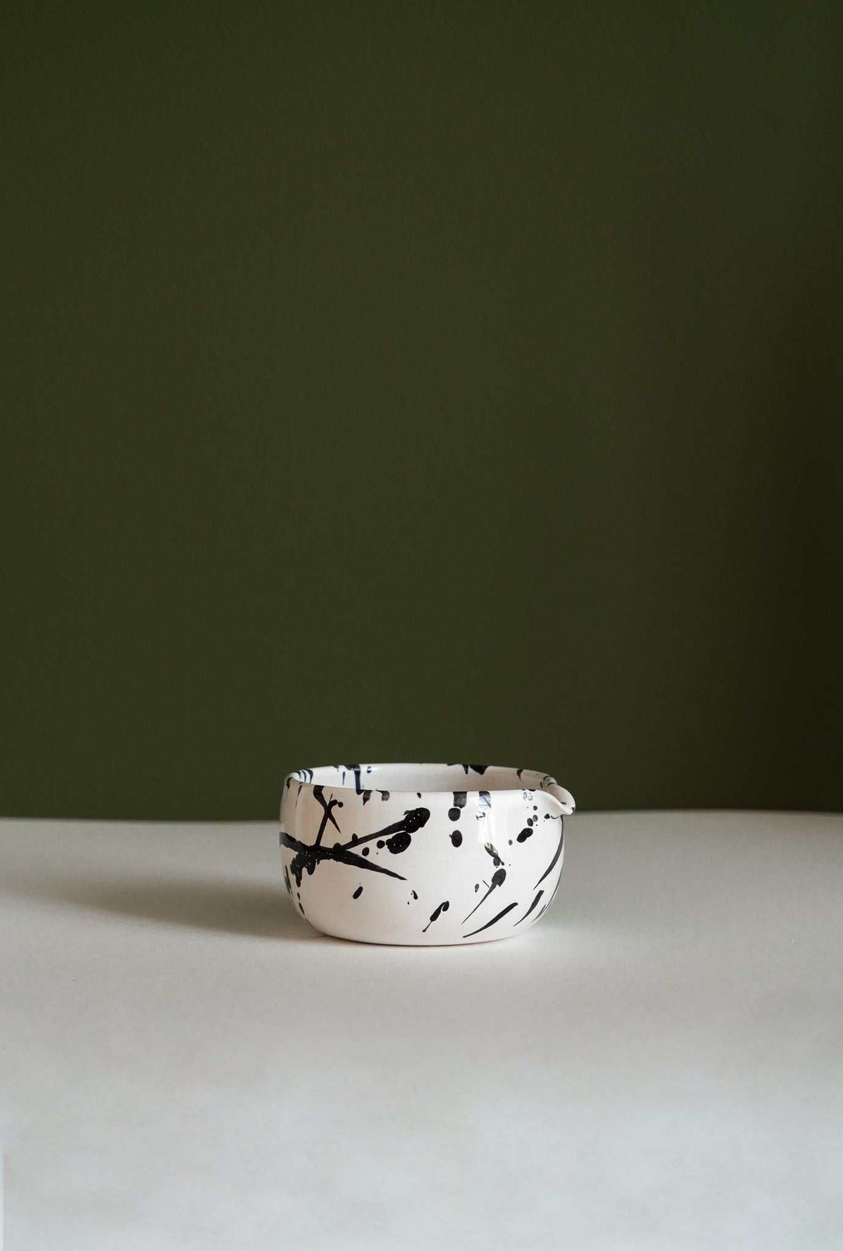 Handmade Matcha Bowl in white stoneware with bold black splatter strokes, rounded shape, and a subtly uneven rim.