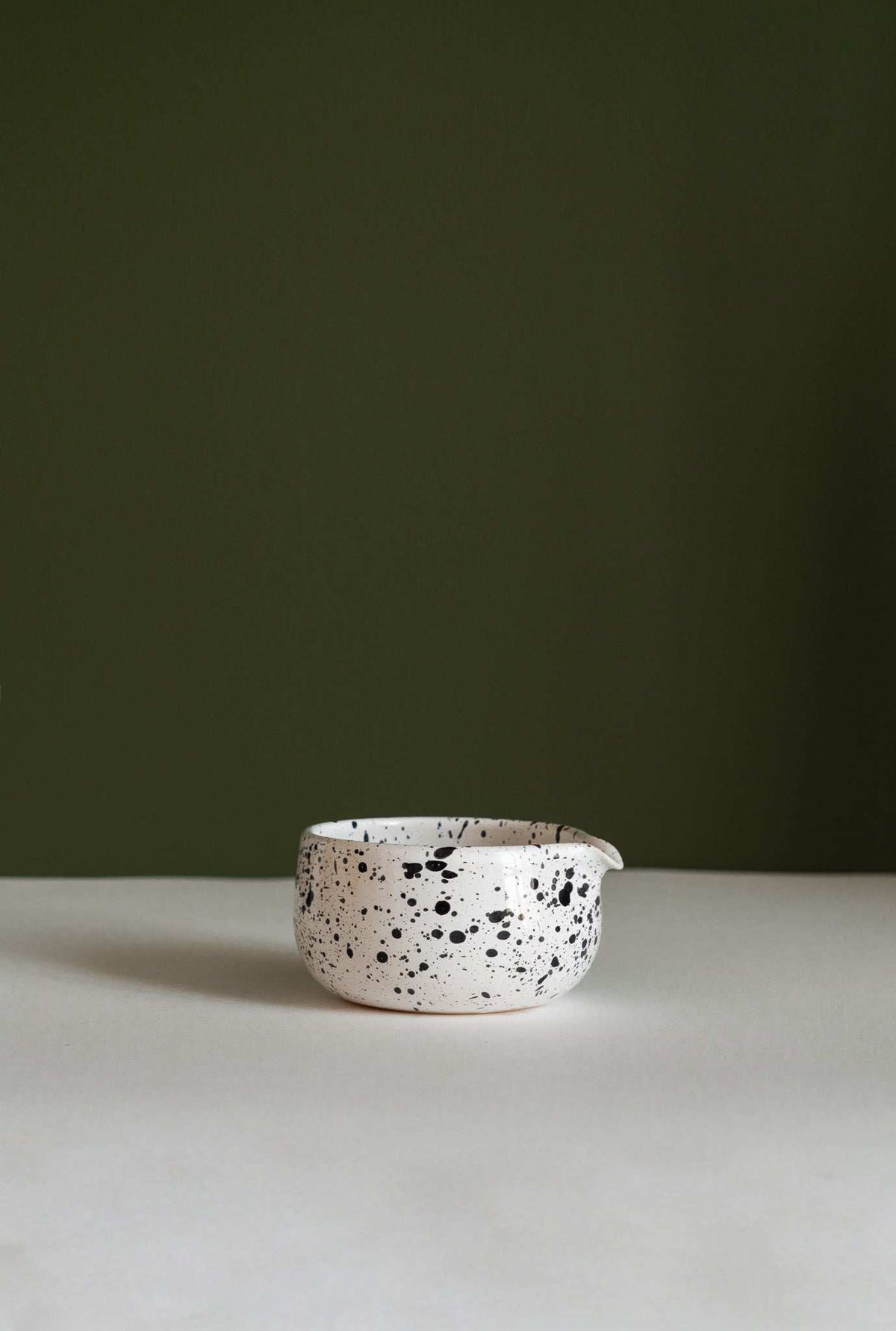 Handmade Matcha Bowl in white glazed stoneware, with irregular black speckles and a rounded, wide shape.